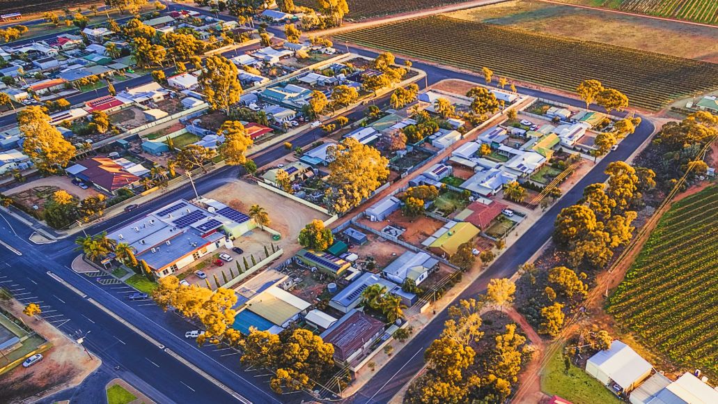 Aerial view of a country town showing houses, streets, trees and paddocks.
